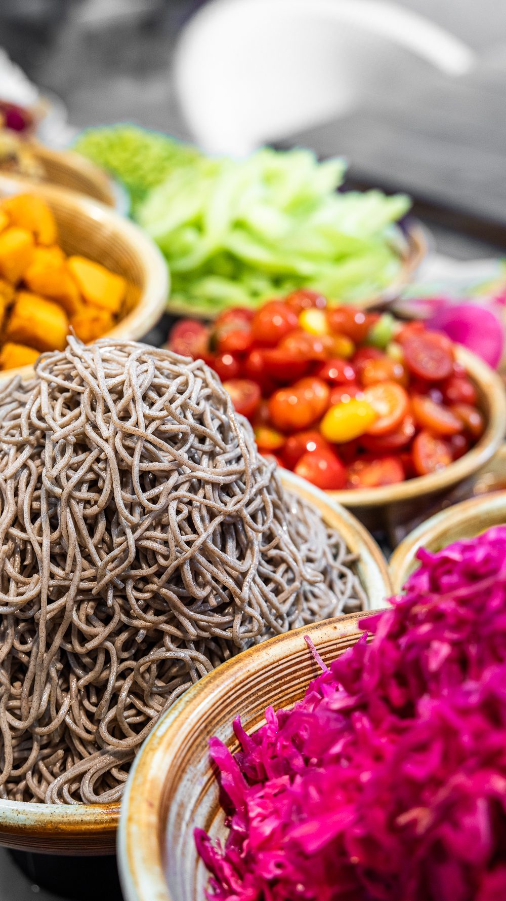 Close-up of salad bar bowls with beetroot, tomatoes and noodles